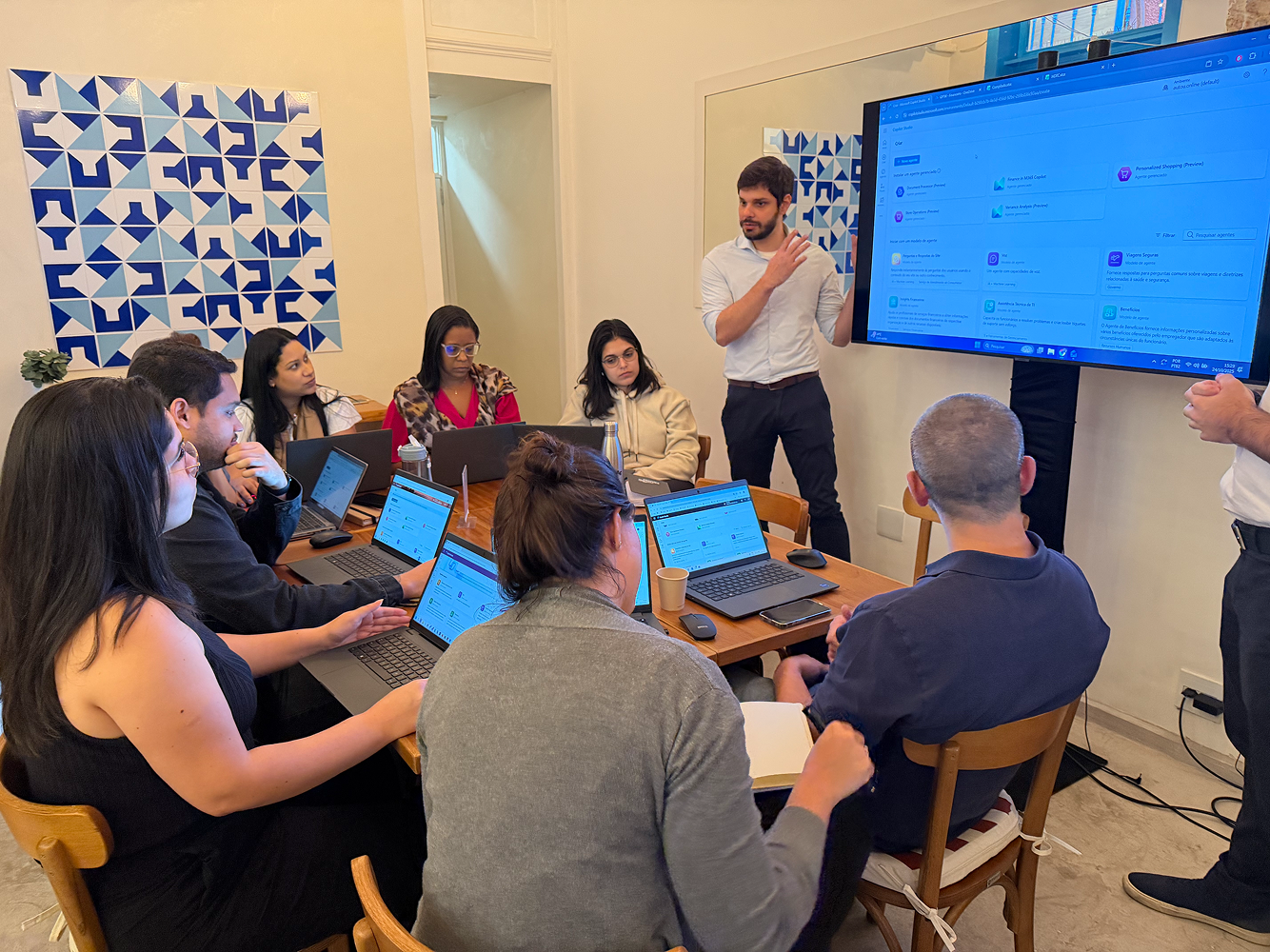 Equipe trabalhando com laptops em frente a um monitor